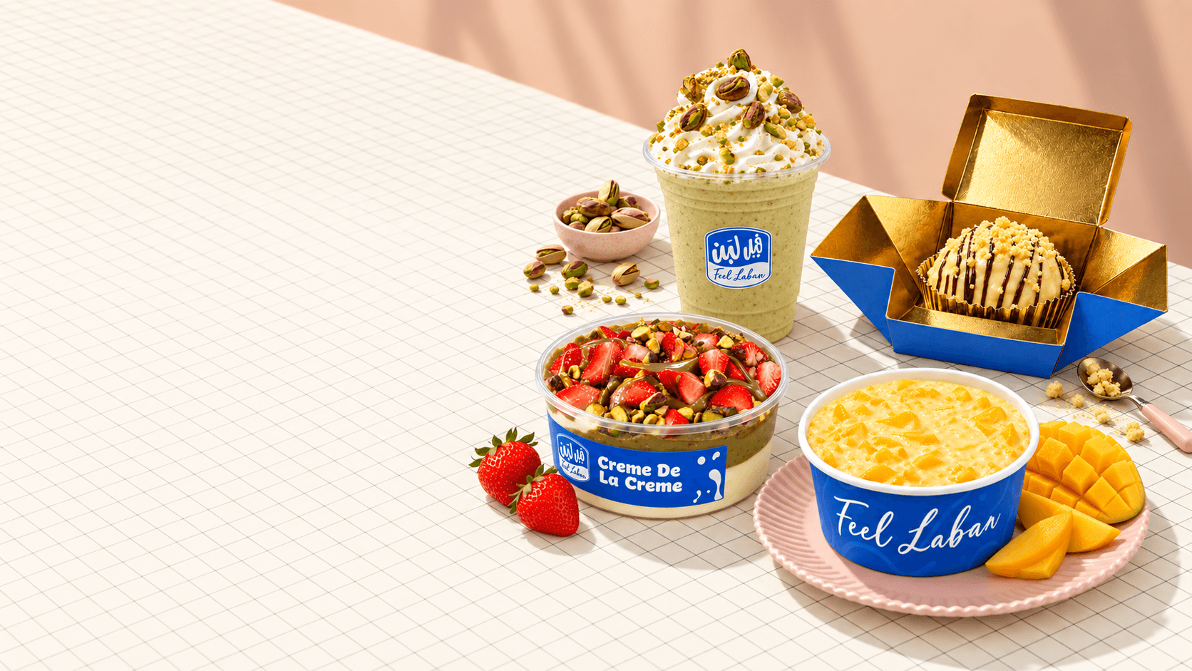 Feel Laban pistachio milkshake, strawberry creme jar, mango pudding and a gold dessert box on a tiled table